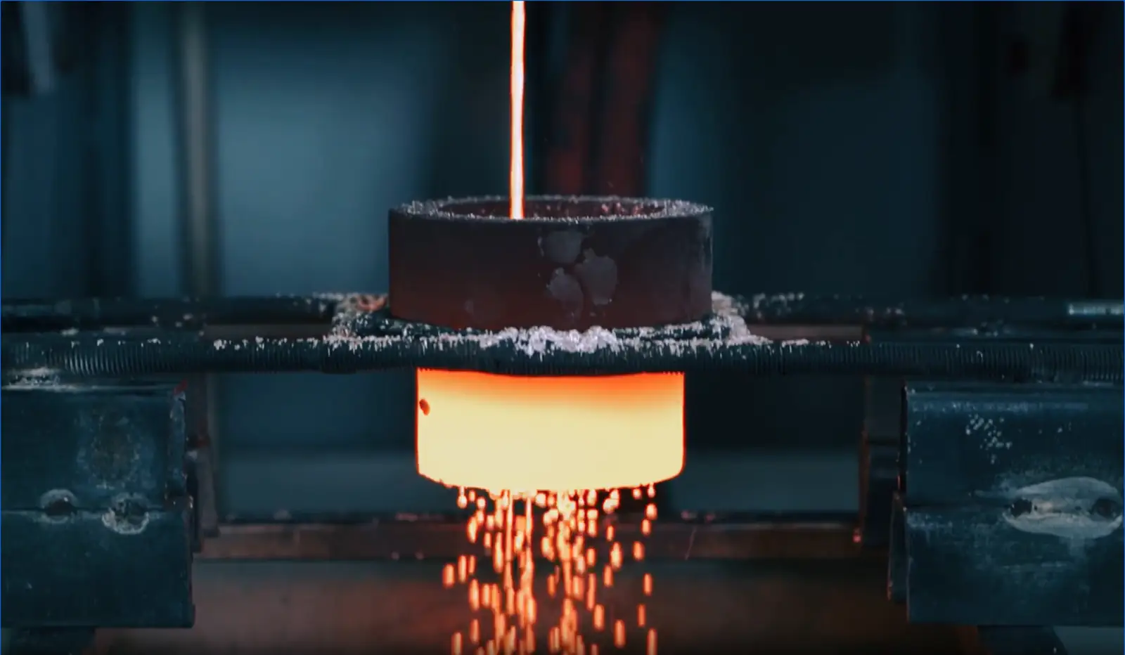 Molten metal pouring from an induction furnace into a crucible, granulating as it cools